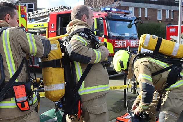 Firefighters putting on breathing apparatus